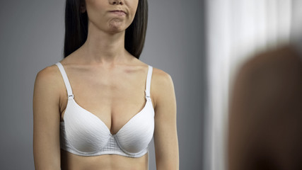 Fototapeta premium Female dissatisfied with her breast shape reflection in mirror, beauty, closeup