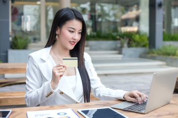 Young asian woman holding credit card and using laptop. Online shopping concept