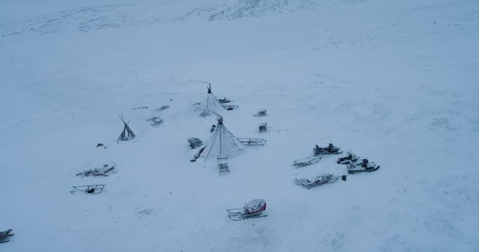 In the Arctic people living in yurts video taking of drone , reindeers with sleigh are driving around the yurts amazing video.