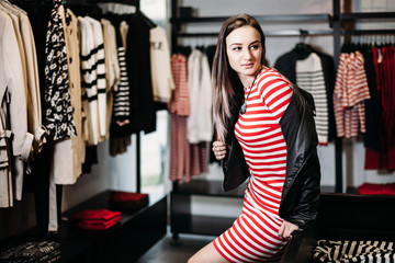 The young pretty woman choosing, trying and buys dresses at shop clothing. Banner for online store...