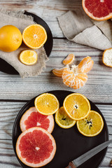 Delicious various types of citrus fruit in plates on wooden background
