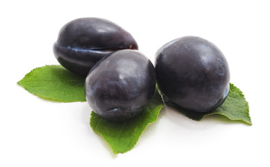 Group of plums with plum leaves.