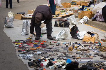 Old man presents his products at the road at the flea market