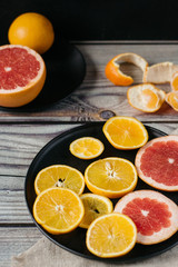 Delicious various types of citrus fruit in plates on wooden background