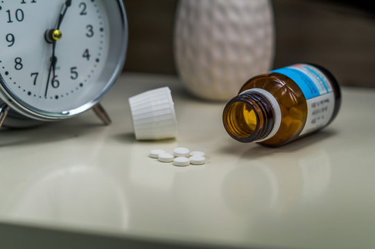 Pillenglas und einzelne Pillen auf einem Nachttisch. Einnehmen der Medizin.