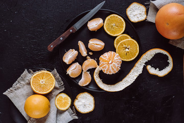Delicious various types fresh cut of citrus fruit in plates on dark background