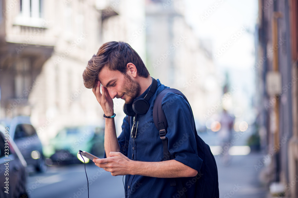 Poster Young teenager using phone on the street