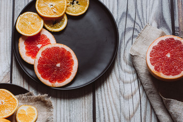 Delicious various types of citrus fruit in plates on wooden background