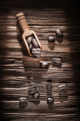 Roasted coffee beans in scoop on vintage wooden board