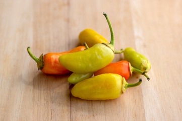 Group of hot peppers jalapeno numex pinata kind, yellow and orange color on wooden table, mexican cuisine very hot ingredients