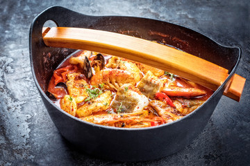 Traditional Italian American cioppino fish stew with prawns, mussels and fish as top view in a modern design Japanese cast-iron roasting dish