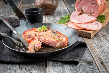 Traditionelle Allgäuer Kalbsrolle als Wurst als Scheibe gebraten in einer schmiedeeisernen Pfanne als closeup