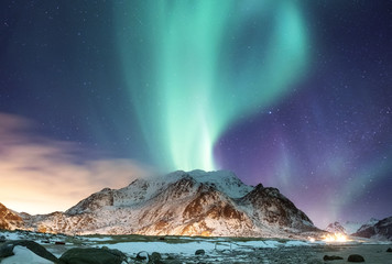 Fototapeta na wymiar Aurora borealis on the Lofoten islands, Norway. Green northern lights above ocean. Night sky with polar lights. Night winter landscape with aurora and reflection on the water surface. 