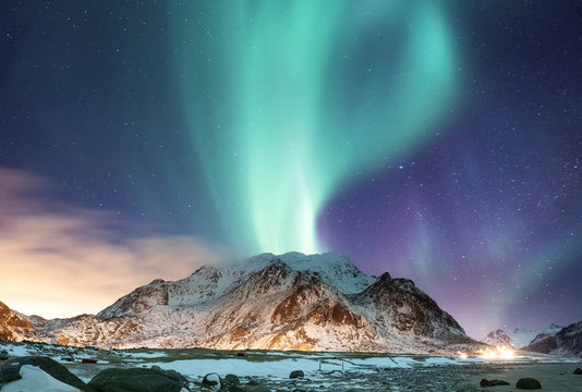 Aurora borealis on the Lofoten islands, Norway. Green northern lights above ocean. Night sky with polar lights. Night winter landscape with aurora and reflection on the water surface. 