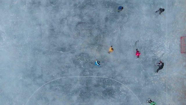 Children skating playing hockey outdoor stadium aerial view from above. Winter sports kids playing hockey drone shot. 