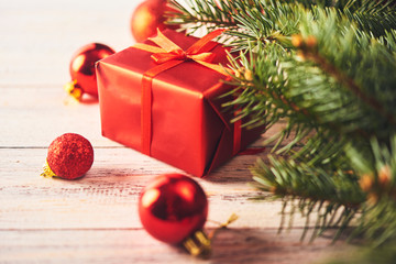 Christmas background. Fir tree and a lot of christmas red baubles and gift box