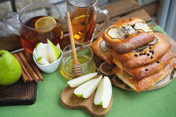 French brioche bun with pear, honey and tea on wooden table