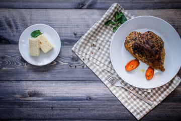 A large piece of baked meat Still life on a light wooden table.