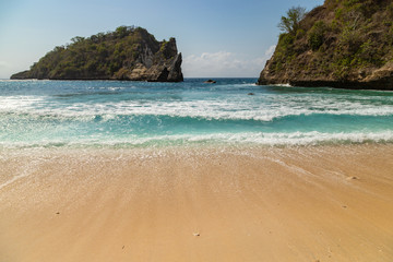 Surf rolling up the beautiful sands of Atuh beach in Nusa penida island in Indonesia.