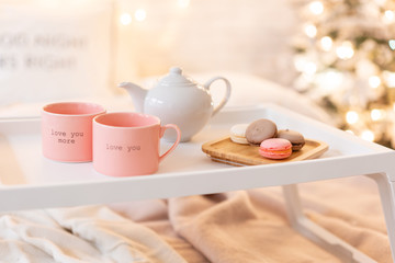 breakfast in bed, tray with cup of coffee and macaroon. Modern bedroom interior. Romantic morning surprise.