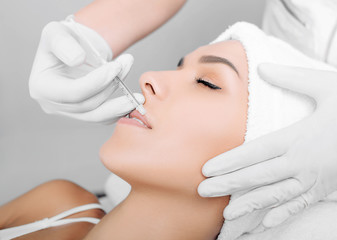 woman having lip injections, a prick of a syringe for the beauty lips. lip augmentation