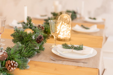 Christmas table setting. Beautiful served table with decorations, candles and lanterns. Living room decorated with lights and Christmas tree.