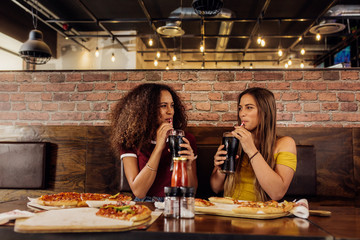 Best friends drinking cola at restaurant