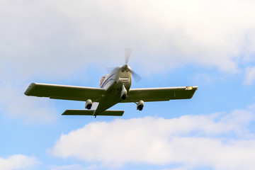 A small plane performs a flight in the background is a blue sky.