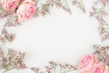Rose fresh flowers with leaves frame on table from above with copy space, flat lay top view scene