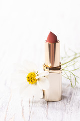 Lipstick and white flower on an shabby wooden background
