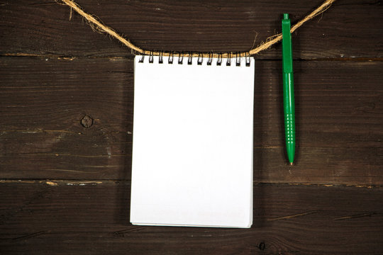 Paper mock up old notebook on a rope on a black wooden board. Place for text. Copy space. Place for announcements.