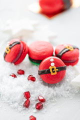 Funny cookie in the form red santa belly on gray table sprinkled with snow. Modern european French cuisine. Christmas theme, Merry Christmas card. New year mood. Variety of sweet macaroons.