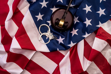 Judge gavel and handcuffs on american flag close up