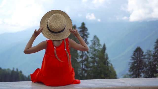 Beautiful happy little girl in mountains in the background of fog