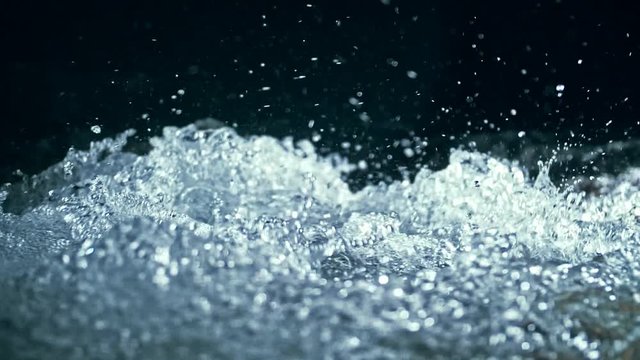 Slow motion of waves on dark water surface with play of flecks of bright light close up. Amazing dramatic natural background. Shooting with 180fps. Epic mystical and magic night view. Crystal clear