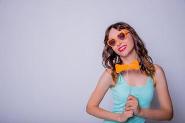 Portrait of crazy trendy chic with beaming smile having carton paper black cutout mustache on stick looking at camera isolated on white background.Paper accessories on a stick for a photo shoot on