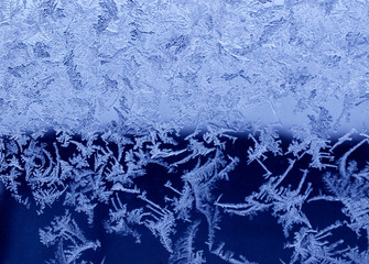 Frosty natural pattern on the window.Frozen patterns on the glass.Winter ice embroidered lace background.Frosted icy texture.Selective focus.