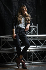 Fototapeta na wymiar Beautiful girl with long curly hair in black leather jacket, t-shirt and jeans