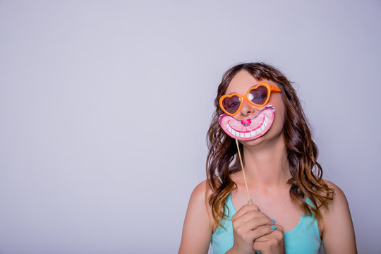 Portrait of crazy trendy chic with beaming smile having carton paper black cutout mustache on stick looking at camera isolated on white background.Paper accessories on a stick for a photo shoot on