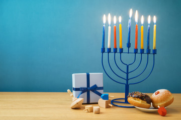 Jewish holiday Hanukkah background with menorah, sufganiyot, gift box and spinning top on wooden table © maglara