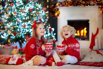 Obraz na płótnie Canvas Kids at Christmas tree. Children drink hot cocoa.