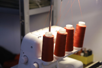 red yarn spools on a white sewing-machine in a tailor´s studio