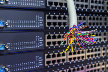 A damaged telephone cable is located on the background of empty server hardware ports. Multicolored...
