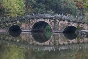 Chinese bridge reflected in river surrounded by autumn foliage