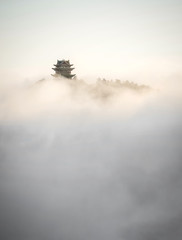 Buddhist temple showing through fog and clouds on mountain top, Emei Mountain, China