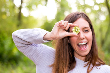 Young Caucasian european woman holding a bitcoin or cryptocurrency smiling happy looking straight ahead with open mouth and perfect smile