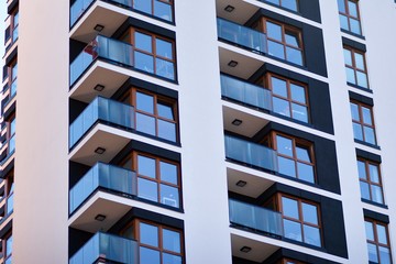 Fragment of a facade of a building with windows and balconies. Modern home with many flats.