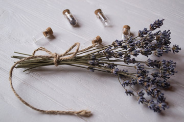 The bunch of lavender, and small glass bottles on a white wooden table.