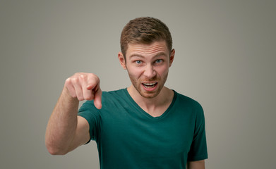Portrait of a grumpy bearded man, angrily screaming, pointing his index finger directly at the...