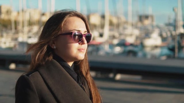 Woman in sunglasses walking with a lot of yachts and boats behind. Slow motion